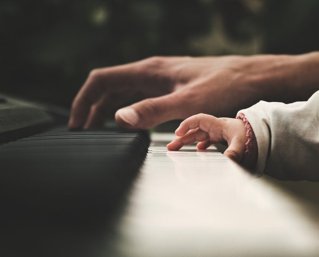 Close look of the baby and man playing the keyboards
