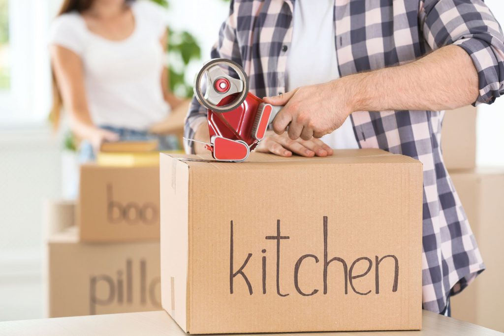 Man taping a package labeled as "kitchen"