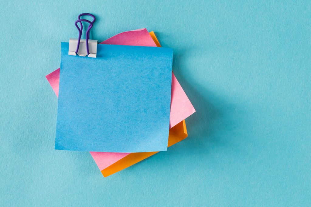 Blue, pink, and orange sticky notes taped to a blue wall