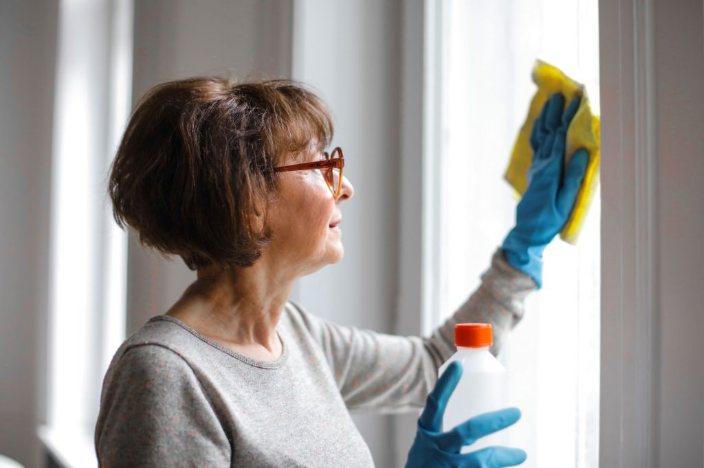 Woman polishing windows before her chosen Chicago movers arrive 