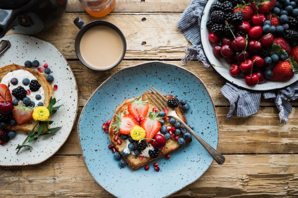Two platters with toast, one full of cherries and blueberries