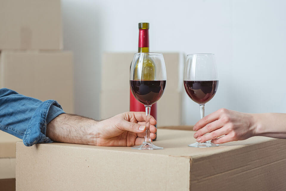 Man and woman holding stemware, a bottle behind their hands