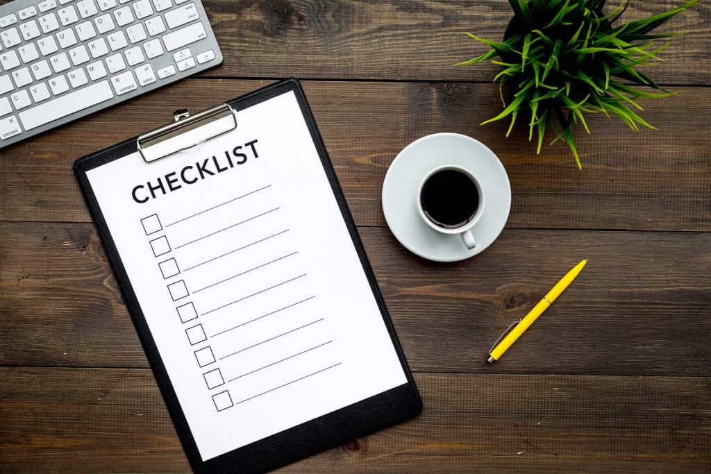 Keyboard, checklist, coffee, plant, and a pen