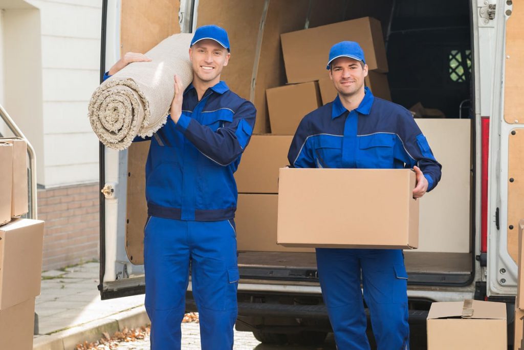 A mover in Chicago, IL, carrying a package and another one holding a carpet