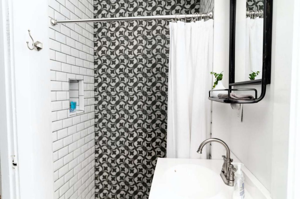 White bathroom with a sink, mirror, and bathtub
