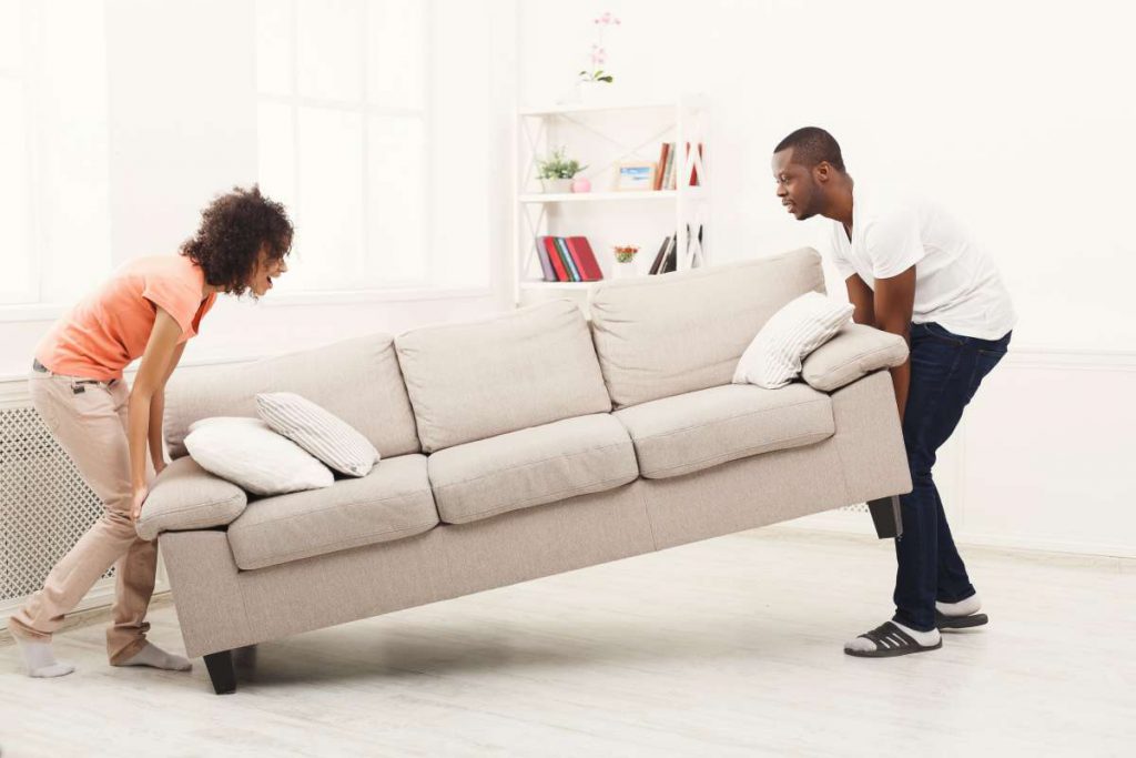 A couple trying to move a couch without professional movers in Chicago