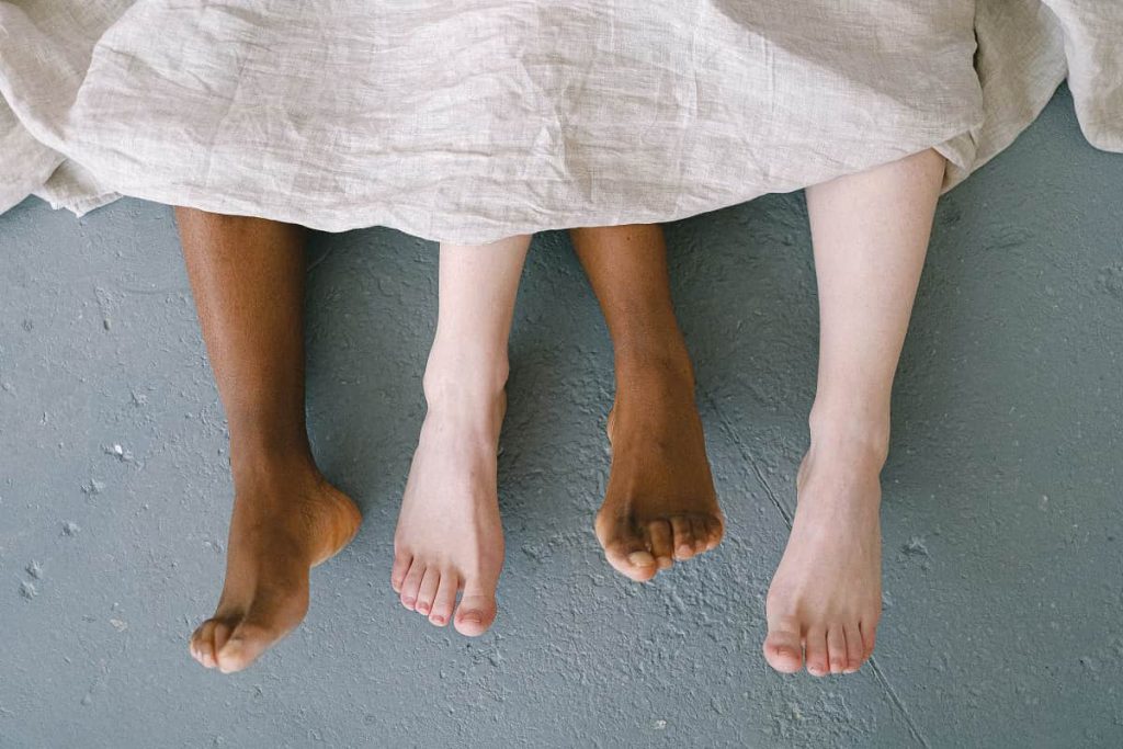 Bare feet of a couple coming out of sheets