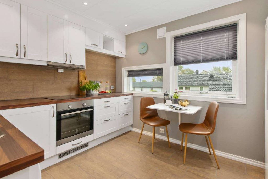 Small white kitchen with two wooden chairs and a white table