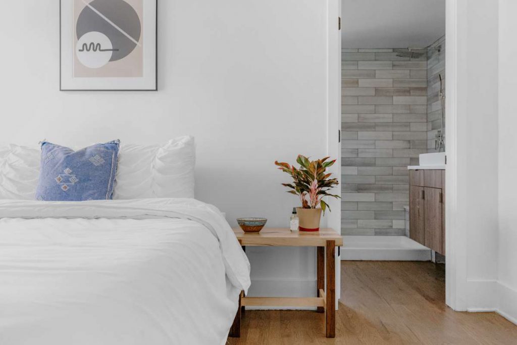 Bed, nightstand, painting, and a door to the bathroom