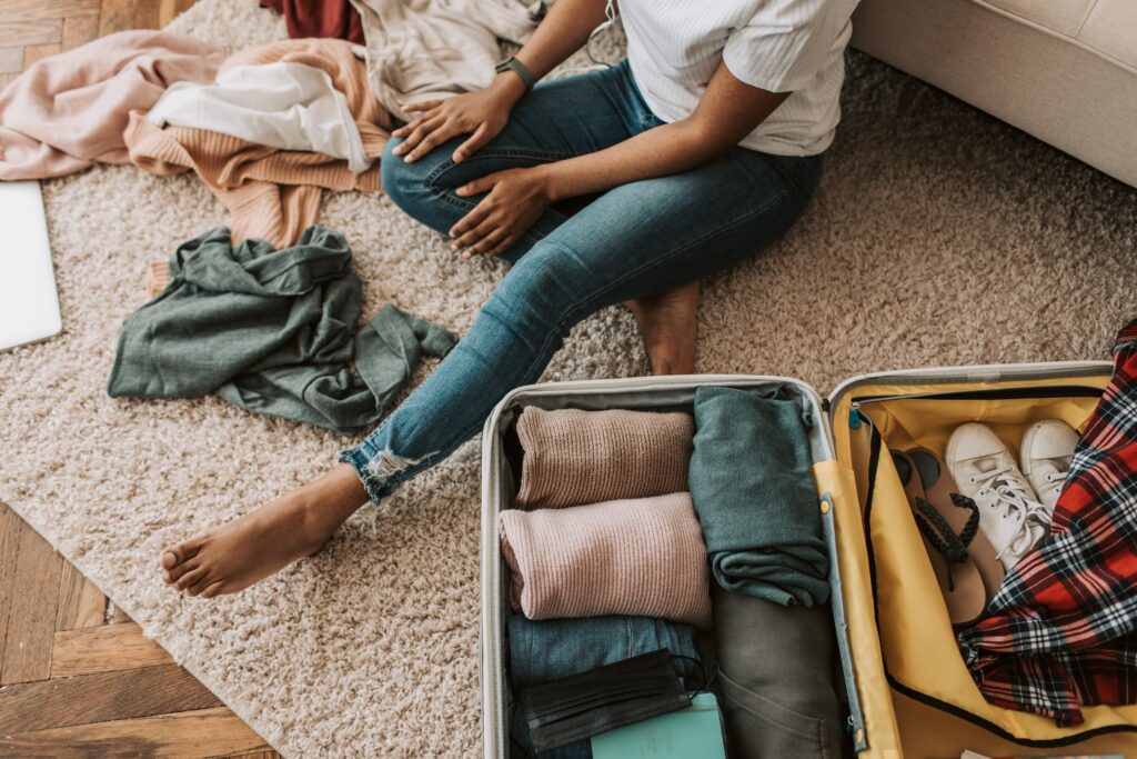 A woman sitting on the floor and packing her suitcase