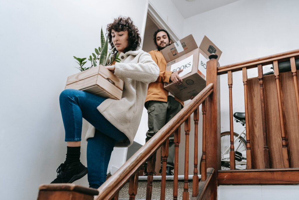 A couple carrying boxes down the stairs